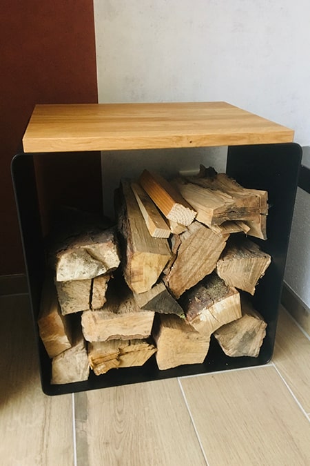 Brennholz-Lager aus schwarzem Stahl auf hellen Bodenfliesen: 3mm Massivstahl eliminiert Wackelgefahr bei voller Beladung – Referenzen in Frankfurt.