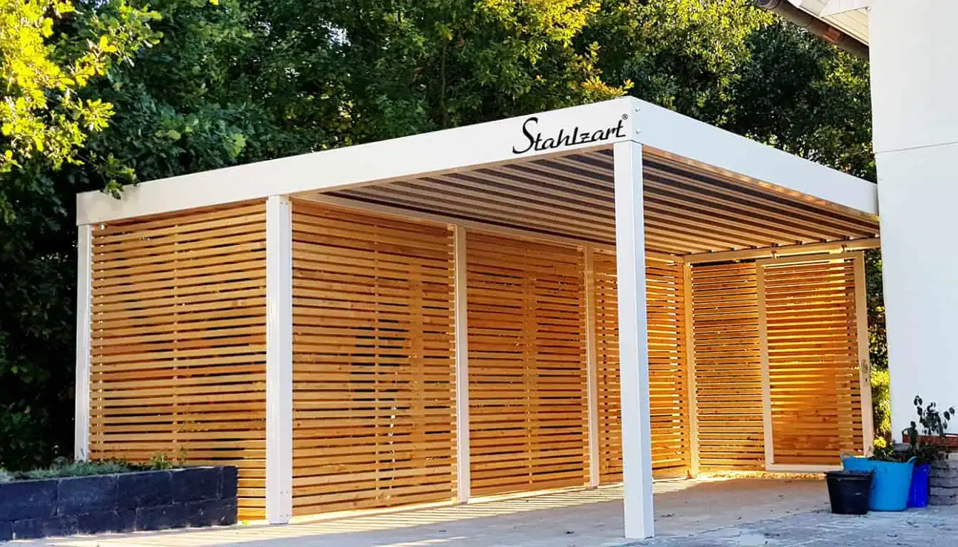 Ein weißer Stahlzart Carport mit integriertem Schuppen und Wänden aus hellen Lärchenholz-Lamellen, der Schutz und Stauraum kombiniert.