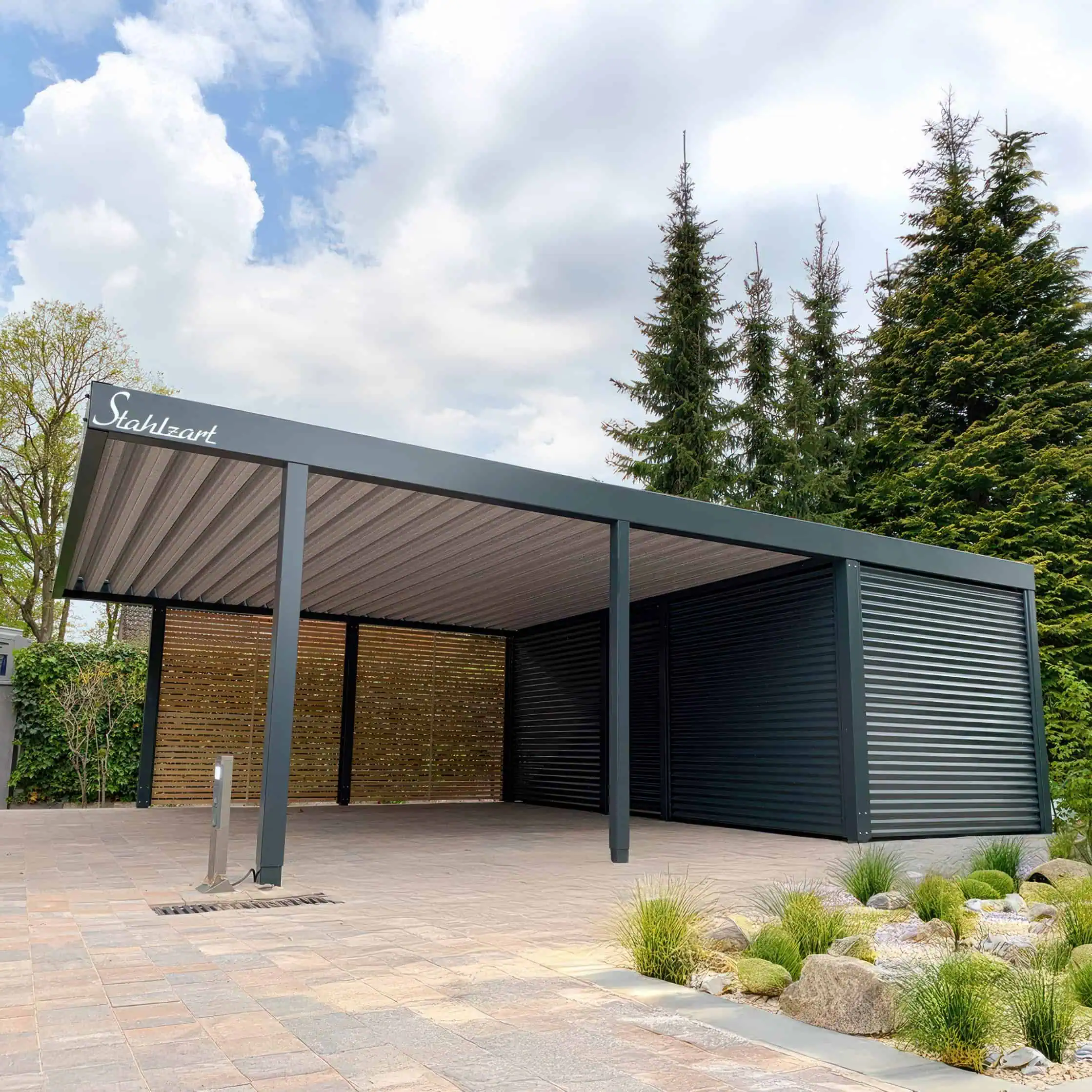 Stahlzart Doppelcarport mit Geräteraum und Holz-Seitenwand Moderner Stahlzart Doppelcarport in Anthrazit mit einem großen Geräteraum an der Rückseite aus Blechwelle und einer offenen rechten Seitenwand aus Holz als Design-Akzent.
